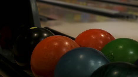 closeup of hand picking up bowling ball and putting it back at indoors bowling alley