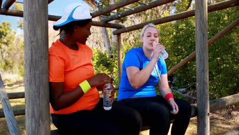 Amigos-Bebiendo-Agua-Después-Del-Entrenamiento-Durante-La-Carrera-De-Obstáculos.