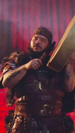 contemporary shaman in traditional leather clothes prays to pagan gods playing shamanic drum in ail. atmospheric performance of old altai culture