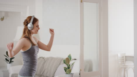 happy young woman dancing at home wearing headphones listening to music celebrating with funky dance moves enjoying freedom having fun on weekend 4k