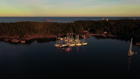 Aerial-view-away-from-Jussaro-island-marina,-sunny,-summer-evening-in-Finland---pull-back,-drone-shot