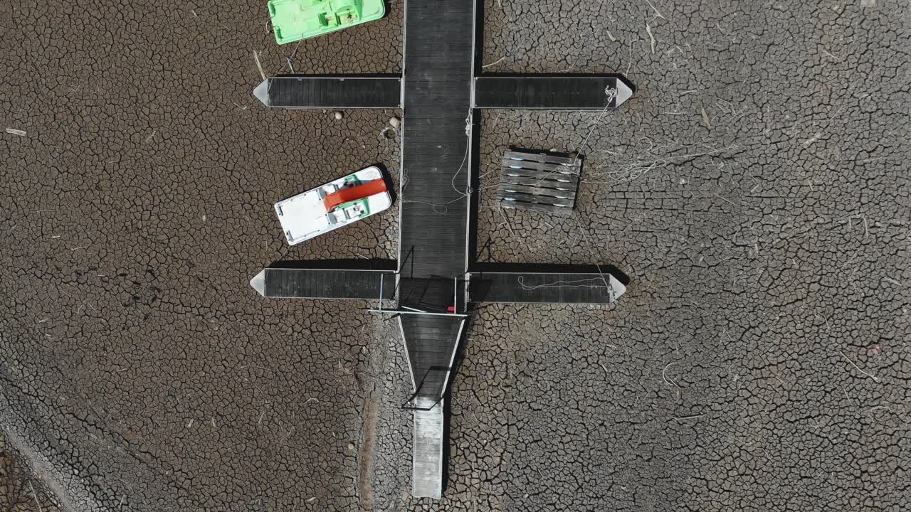 Empty reservoir and empty jetty on cracked ground