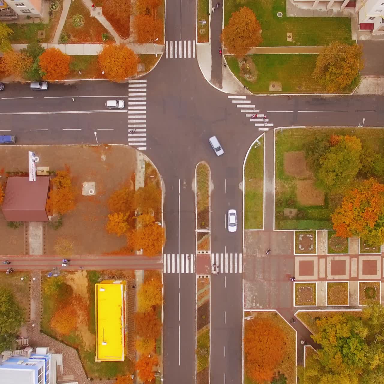 Crossroads on the roads of urban city. Transport and people moving by the streets of the city. Top view on the area in autumn season