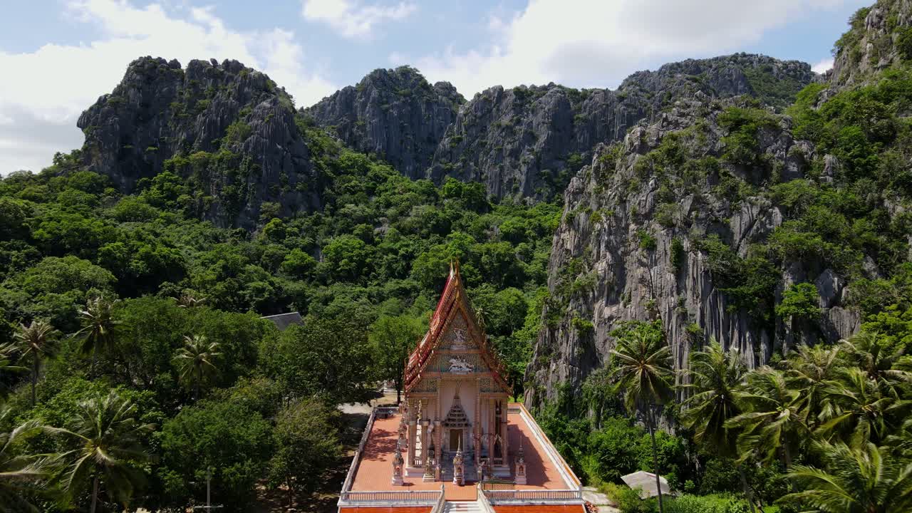 imagens aéreas de uma altitude vantajosa mais alta em direção a este adorável templo revelando montanhas, coqueiros e floresta, wat khao daeng, parque nacional khao sam roi yot, phrachuap khiri khan, tailândia