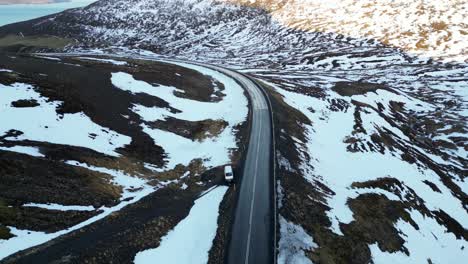 Car-Parked-on-Scenic-Icelandic-Road-with-Snow-Patched-Landscape-AERIAL