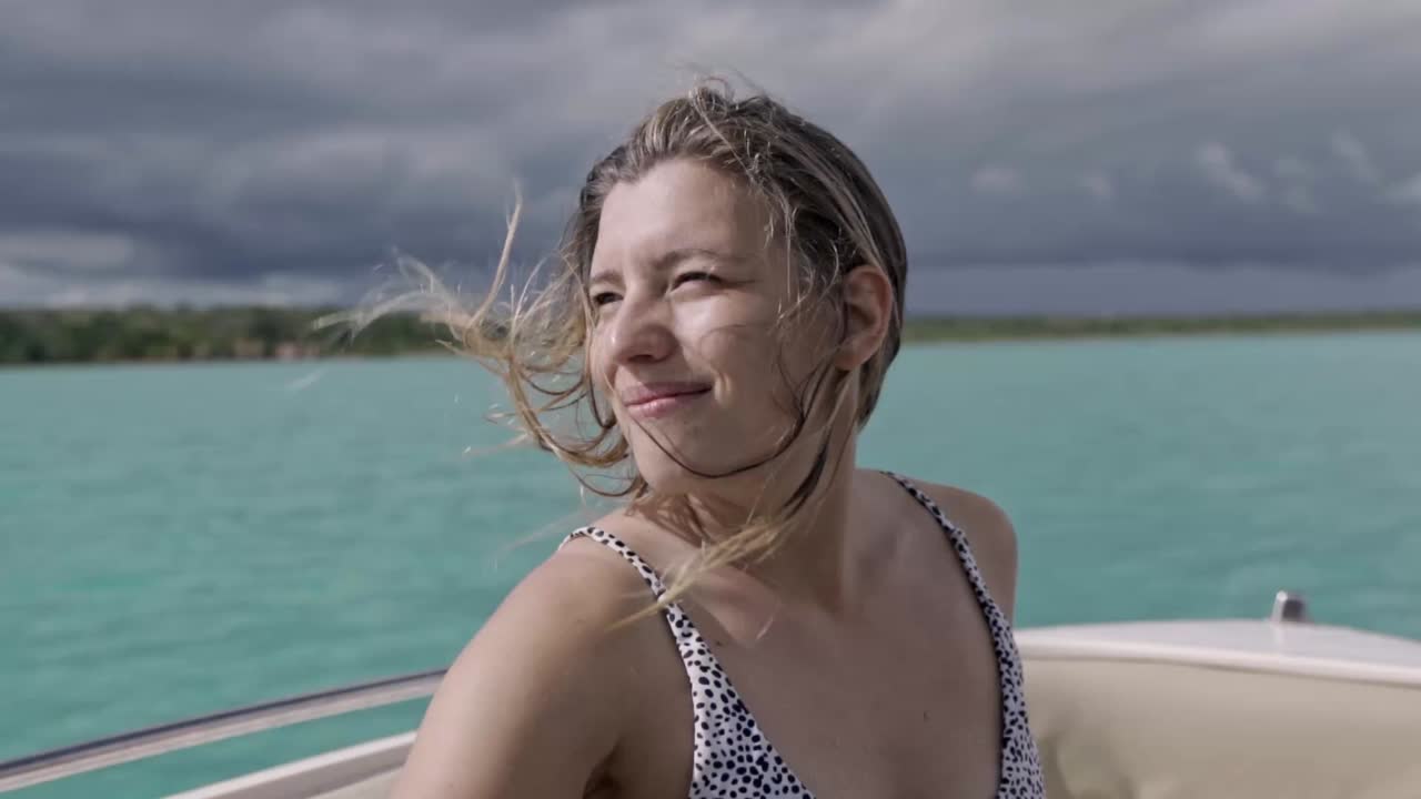 Young woman on a boat with the turquoise waters of the Laguna de Bacalar and a brooding stormy sky in the background, capturing a moment of serenity in Quintana Roo, México