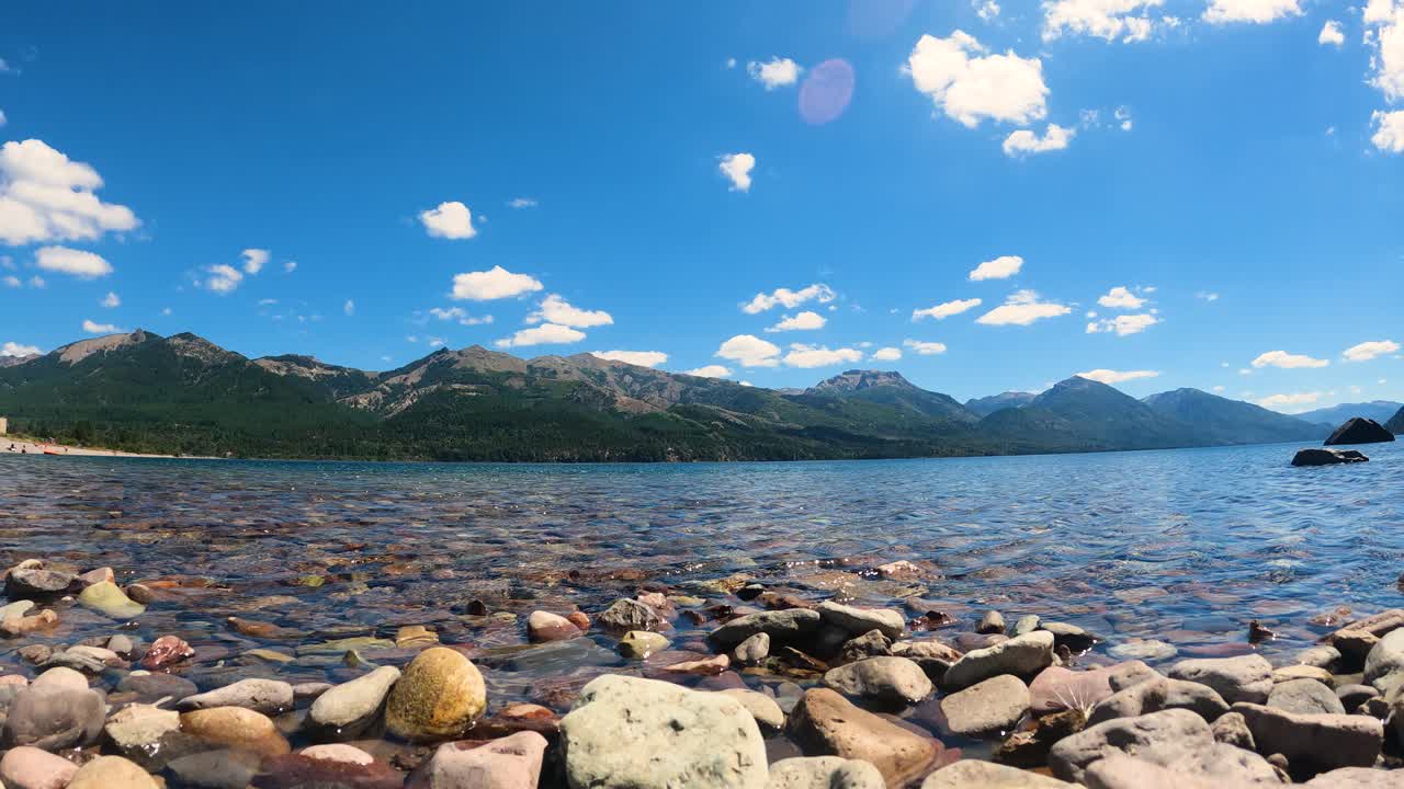 tiro de lapso de tiempo del lago tranquilo con montañas en el fondo durante el hermoso día soleado y las nubes en movimiento
