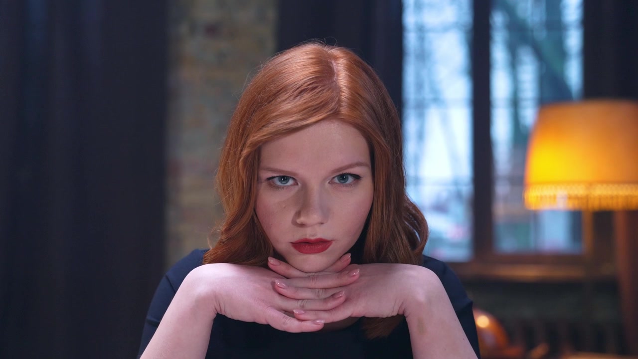 Serious Redhead Woman Looking at Camera with Thoughtful Hand Gesture