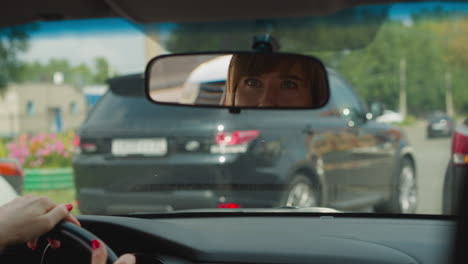 reflejo de una mujer en el espejo retrovisor en el parabrisas de un coche