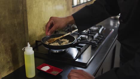 caucasian male chef frying vegetables on a pan