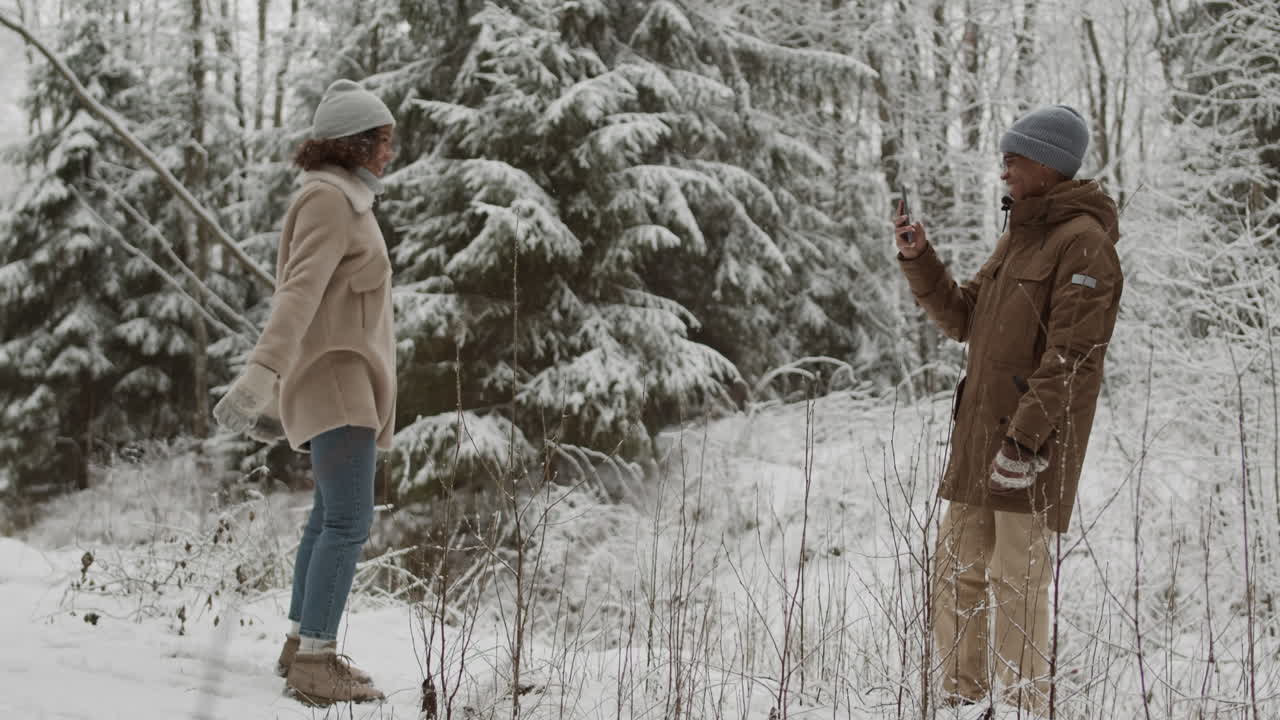 una pareja tomando una foto en un bosque nevado