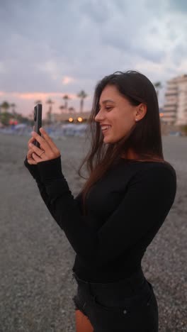 woman taking photo on beach at sunset