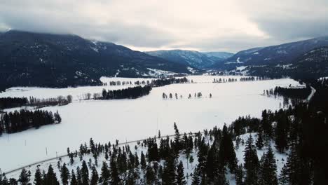 Snow-Covered-Fields-and-Wooded-Slopes-in-the-Thompson-Nicola-Region,-Canada,-Breathtaking-Aerial-View-of-the-Backcountry-Farm-and-Ranch-Life-in-the-Wild-Wilderness-of-British-Columbia