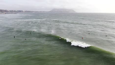 video aéreo de 4k filmado durante el día de un surfista atrapando y montando una ola en las aguas costeras del océano pacífico en lima, perú