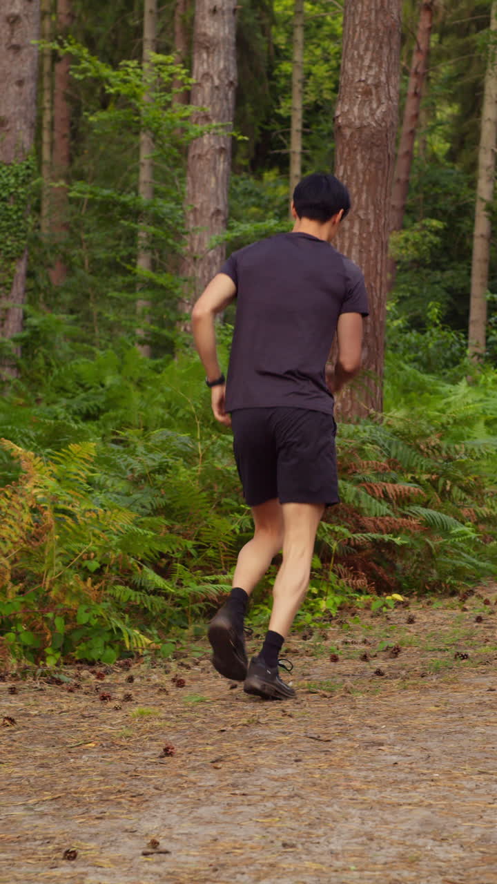 Vertical Video Of Tired Man Exercising Doing Work Out Outdoors Running Along Track Through Forest Stopping To Catch Breath Shot In Real Time 1