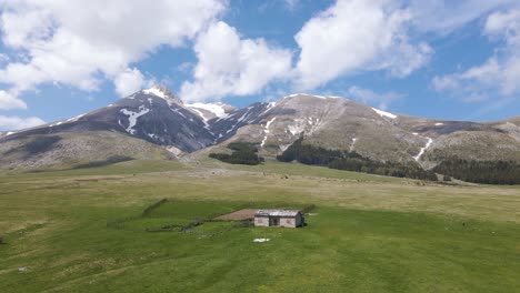 wide angle scene of an old sheppards shelter in a grassland valley surrounded by the gran sasso mountain range in the rural countryside of abruzzo in italy