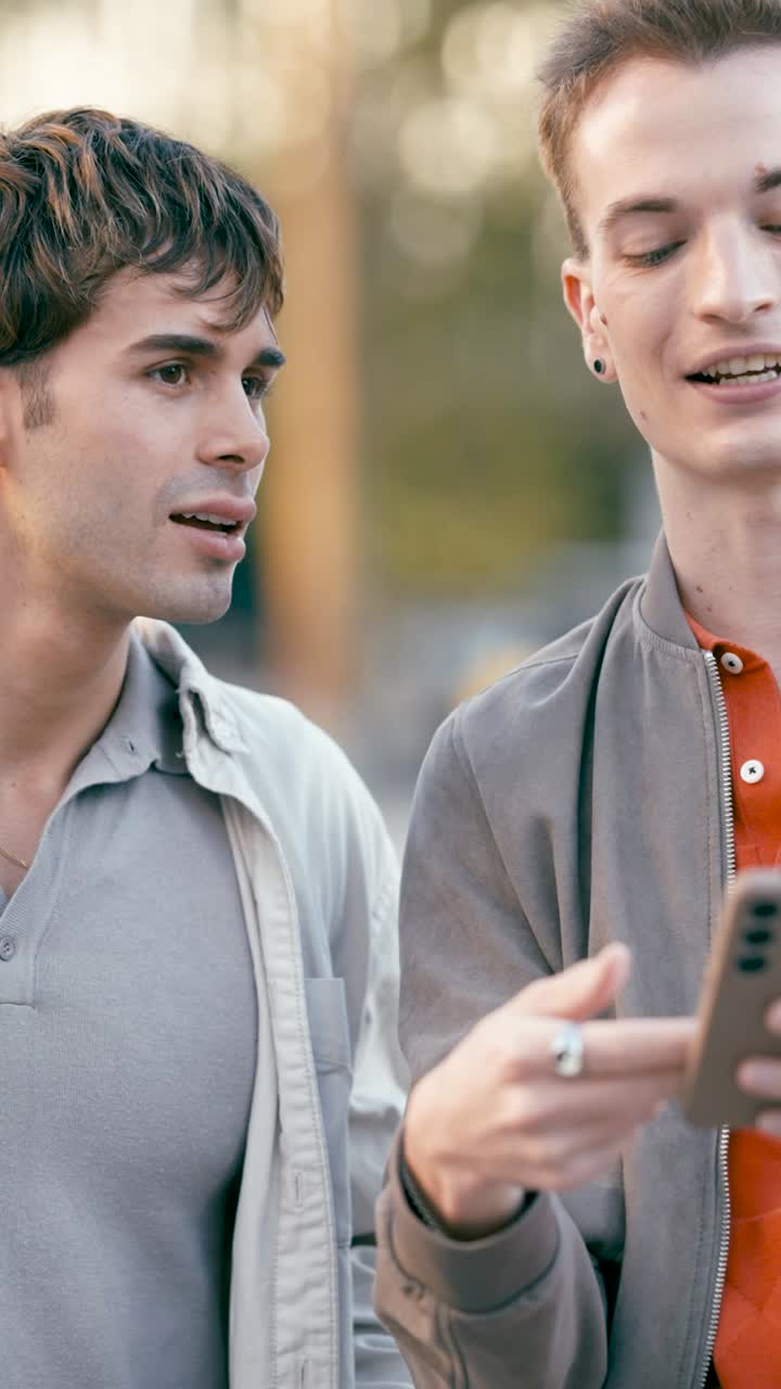 Two young men looking at a smartphone outdoors