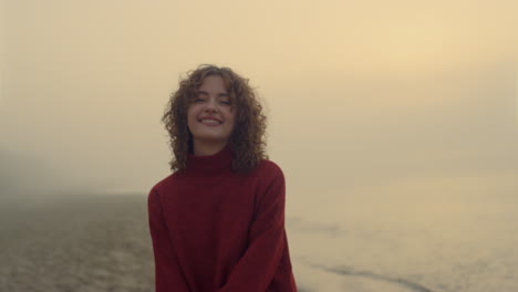 Smiling-girl-posing-at-camera.-Happy-woman-posing-on-sea-beach-at-sunrise