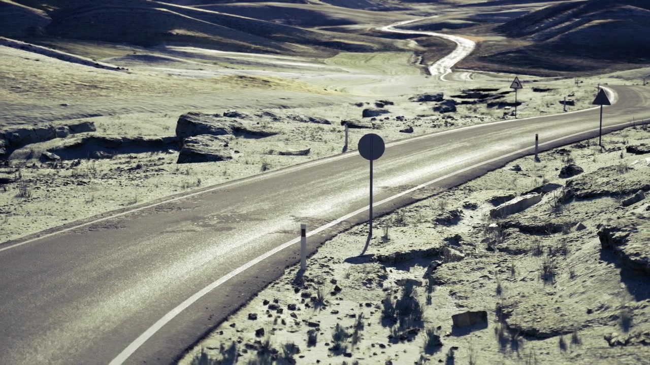 Strada tortuosa che si snoda attraverso la macchia con pavimentazione riflettente.