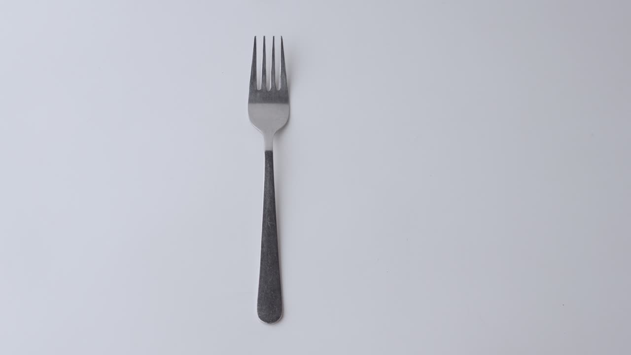 cuchara y una cuerda de ropa en primer plano con un fondo blanco, la cuchara está siendo levantada por una mano