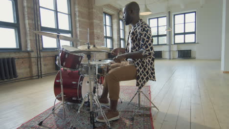 black drummer playing drumkit in studio