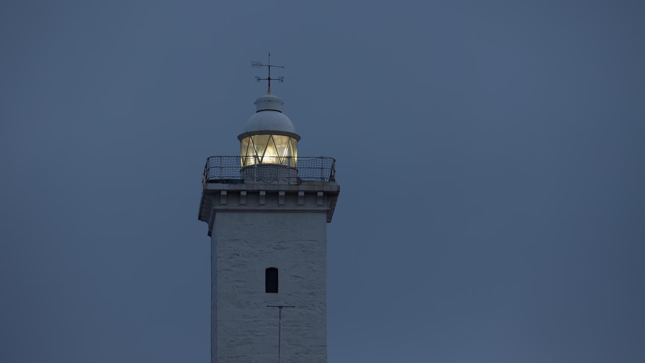 Obracająca się latarnia morska na tle wieczornego nieba o zmierzchu, miejsce na tekst