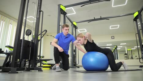personal trainer assisting woman with exercise ball