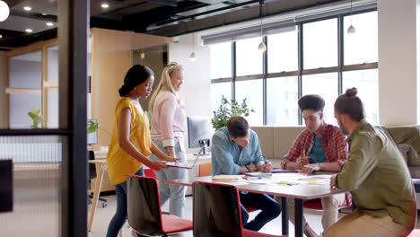 happy diverse colleagues brainstorming with laptop at table in office in slow motion
