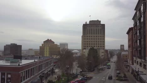 drone flying above downtown tacoma towards tall buildings with distant view of the famous tacoma dome - aerial