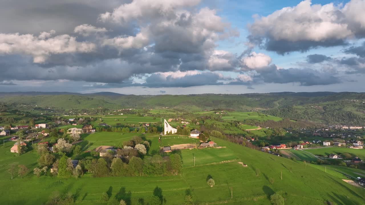 시골의 매력: 드론이 진행 ⁇ 에 따라, 그것은 평화로운 봄 저녁에 현대적인 언덕 꼭대기 교회를 드러 ⁇ 니다. 평화로운 시골과 마을을 내려다보며, 극적인 구름에  ⁇ 여 있습니다.