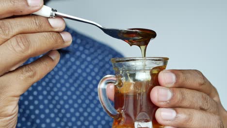 person pouring honey into a small glass cup
