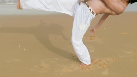 un tipo bailando capoeira en la playa.