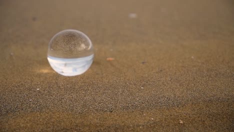 bola de cristal que se refleja al revés con efecto de zoom en una playa en un día nublado y ventoso de invierno