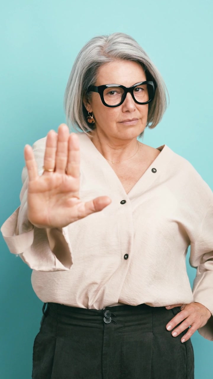 Mature Woman Making a Stop Gesture Against a Blue Background