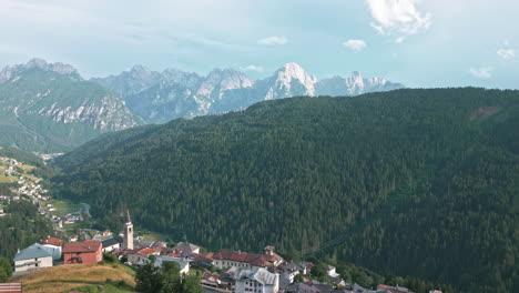 Video-De-Drones-Volando-Por-La-Histórica-Iglesia-Católica-En-La-Ladera-De-La-Colina-En-El-Casco-Antiguo-Rodeado-De-Granjas-En-Los-Dolomitas-Italia-Con-La-Cordillera-En-El-Fondo-Al-Atardecer-Hora-Dorada-En-Verano