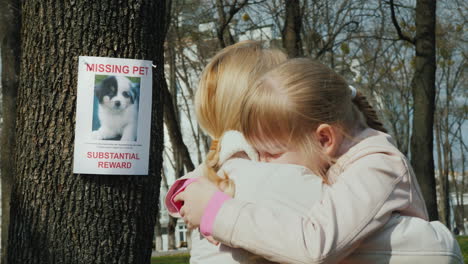 mom soothes the girl who lost the dog on the tree hangs the announcement of the missing puppy