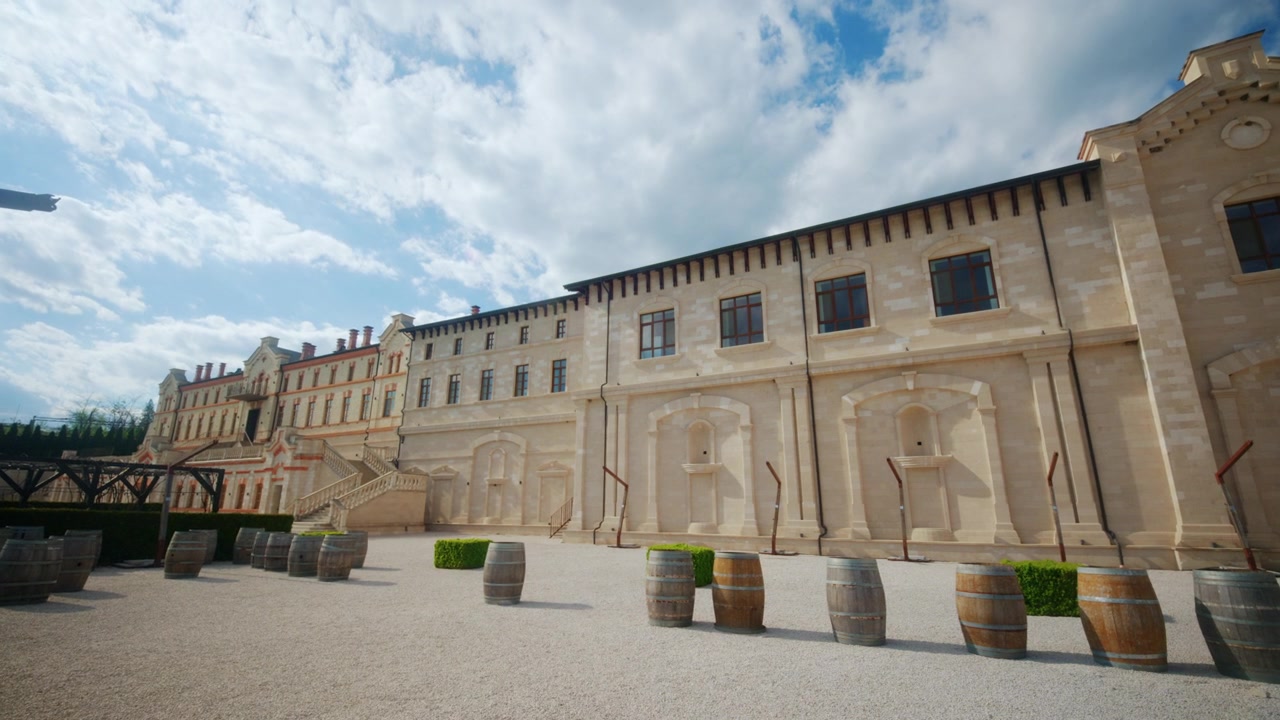 Ampia vista del cortile di un castello vinicolo in Moldavia, che mostra storici edifici vinicoli, facciate in pietra, botti di vino, sentieri di ghiaia e scalinate architettoniche