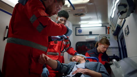 medical doctors taking care about victim on stretchers in ambulance car