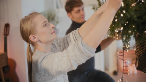 woman decorating xmas tree by male friend