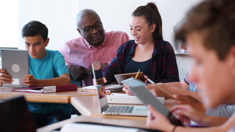 Female-High-School-Student-Receiving-Individual-Attention-From-Teacher-In-Class