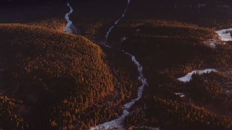 Grúa-Hacia-Arriba-Desde-La-Carretera-Hasta-La-Cordillera,-Una-Luz-Dorada-Brillando-Sobre-El-Bosque-En-El-Medio