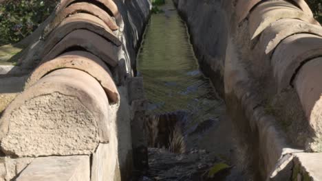 old arabic aqueduct with flowing water in slow motion in spain