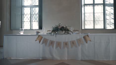 mesa de boda blanca para una pareja de recién casados con una flor y letreros de señor y señora