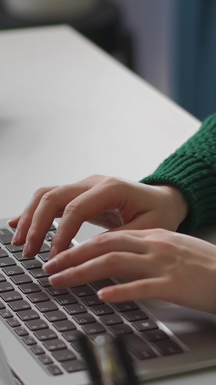 Close-up of Hands Typing on Laptop Keyboard at Desk