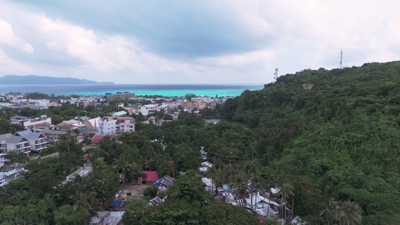 Aerial view of Boracay’s coastal road lined with palm trees, colorful tricycles, and resort buildings with lush green hills in the background. Ideal for travel and lifestyle projects