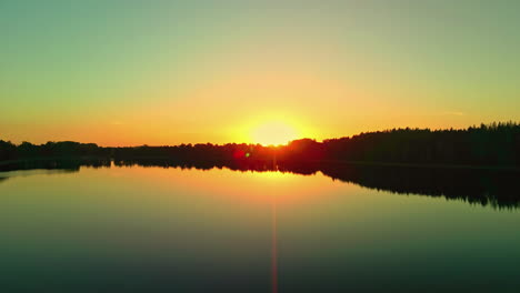 Toma-Aérea-Captura-Un-Lago-Al-Atardecer-Con-Una-Silueta-De-Línea-De-árboles-En-Letonia