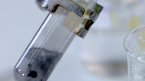 a detailed view of bubbling reaction inside a tilted test tube next to a beaker.