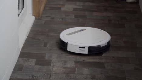 hogar inteligente. la aspiradora robot realiza la limpieza automática del apartamento en un determinado momento. ayudante inteligente en el hogar. un moderno limpiador robótico limpia el polvo en el suelo. tecnología de limpieza