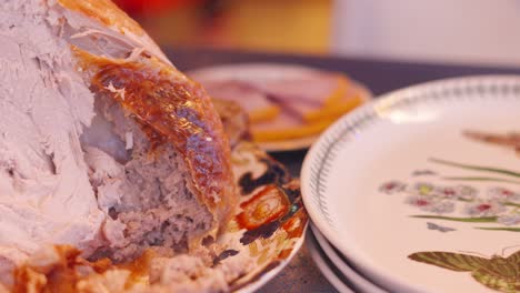 escena de la cena de navidad con pavo descansando en la mesa después de tallar en el plato con rebanadas de jamón asado con miel en el fondo. reunión familiar de la temporada de vacaciones en xmas 4k.