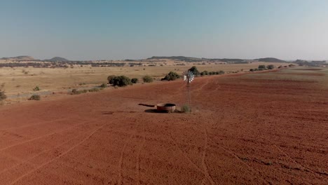 Aerial-close-up-Rotating-shot-of-a-working-windpump-in-a-dry-field